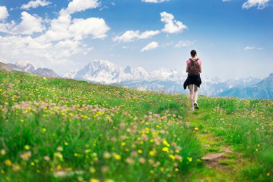 woman-hiking-in-meadow-toward-mountains